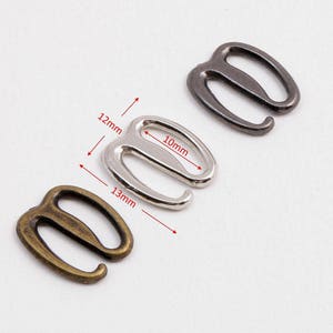 May include: Three metal bra strap adjusters in silver, gold, and black. The silver adjuster is 12mm long and 10mm wide. The gold adjuster is 13mm long.