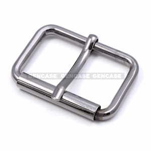 Puede incluir: Una hebilla de metal plateada con forma rectangular y acabado liso.