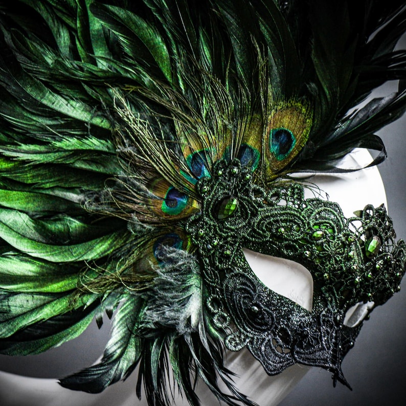 Peut inclure: Un masque de bal masqu&eacute; vert et noir avec des plumes de paon. Le masque pr&eacute;sente des d&eacute;tails de dentelle complexes, orn&eacute;s de pierres pr&eacute;cieuses vertes. Le design int&egrave;gre des plumes vert fonc&eacute; et des plumes de paon avec des accents bleus et dor&eacute;s.