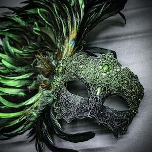 Peut inclure: Un masque de mascarade d&eacute;coratif avec un design moiti&eacute;-moiti&eacute;. Le c&ocirc;t&eacute; droit est noir scintillant, tandis que le c&ocirc;t&eacute; gauche est vert vif, orn&eacute; de dentelle, de bijoux et de plumes. Les plumes comprennent des paons et des plumes vert fonc&eacute;.