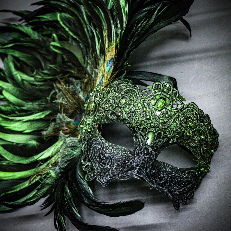 Peut inclure: Un masque de mascarade d&eacute;coratif avec un design moiti&eacute;-moiti&eacute;. Le c&ocirc;t&eacute; droit est noir scintillant, tandis que le c&ocirc;t&eacute; gauche est vert vif, orn&eacute; de dentelle, de bijoux et de plumes. Les plumes comprennent des paons et des plumes vert fonc&eacute;.
