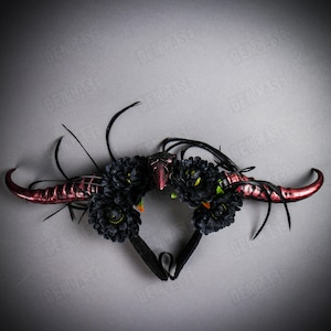 May include: A black headband with red horns and black flowers. The headband is decorated with feathers.