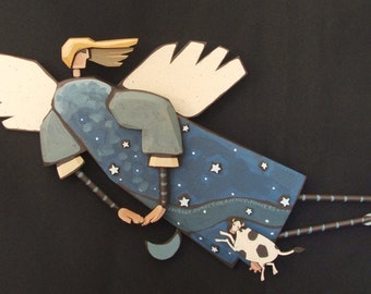 May include: A blue and white angel with wings, flying with a cow in its arms. The angel is wearing a blue robe with white stars and a white halo. The cow is black and white with a pink nose.