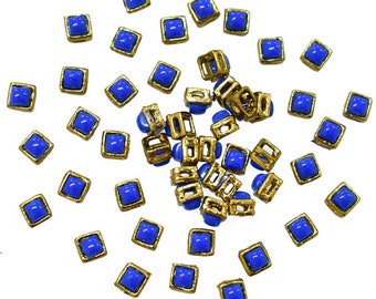May include: A scattering of blue and gold square-shaped embellishments. The embellishments are made of glass and metal.
