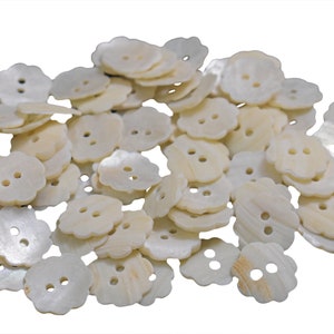 May include: A pile of white shell buttons with two holes each. The buttons are shaped like a flower with five petals.