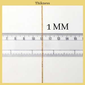 May include: Close-up of a gold chain measured against a ruler. The chain is 1 mm thick.