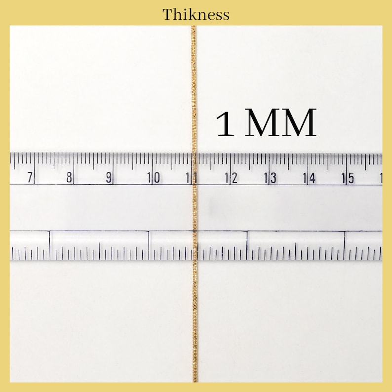 May include: Close-up of a gold chain measured against a ruler. The chain is 1 mm thick.