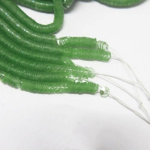 May include: A strand of green iridescent sequins, strung on white thread.