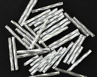 May include: A pile of silver glass beads, each bead is twisted and has a reflective surface.