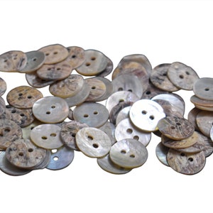 May include: A pile of round, white and brown shell buttons with two holes each.
