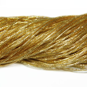 May include: A close-up of a pile of gold metallic cord. The cord is shiny and has a slight sparkle.