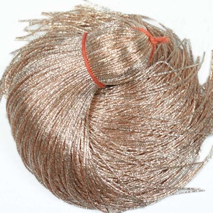 May include: A large bundle of silver and gold metallic cord. The cord is tightly wound and has a shiny, sparkly finish.