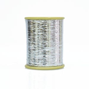 May include: A spool of silver metallic thread with a beige plastic bobbin.