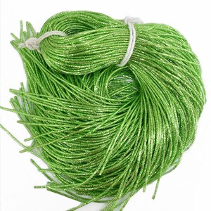 May include: A bundle of green metallic string beads. The beads are small and round, and they have a shiny finish.