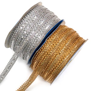 May include: Two spools of decorative trim. One spool is silver, the other is gold. The trim has a woven design with a scalloped edge. The spools are on a white background.