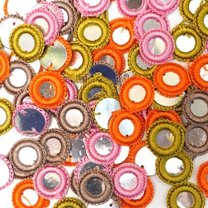 Puede incluir: Surtido de adornos redondos de ganchillo con centros espejados. Los adornos son de varios colores, incluyendo naranja, rosa, verde y marrón.