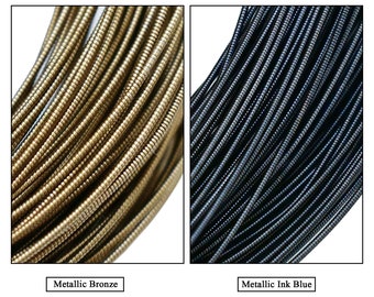 May include: Two spools of metallic wire, one in bronze and one in ink blue. The wire is thin and has a slightly textured surface.