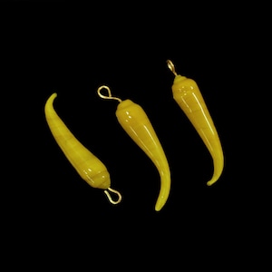 May include: Three yellow glass chili pepper charms with gold loops. The charms are shaped like chili peppers and have a glossy finish.