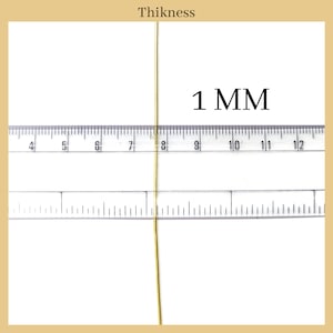May include: A close-up of a gold wire measured against a ruler. The wire is 1 mm thick.  The ruler shows measurements in millimeters.
