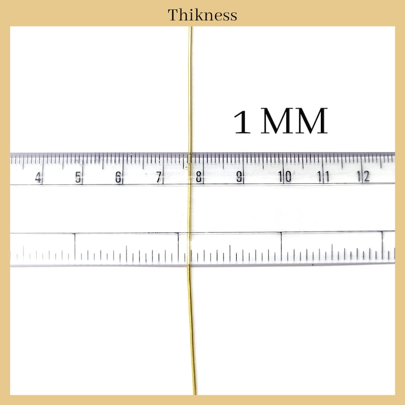 May include: A close-up of a gold wire measured against a ruler. The wire is 1 mm thick.  The ruler shows measurements in millimeters.