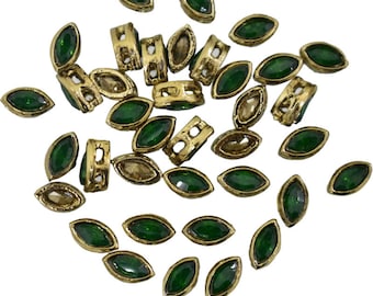 May include: An assortment of gold-toned metal jewelry components. The components include marquise-shaped green gemstones and rectangular pieces with cut-out designs. The gemstones are approximately 0.5 inches long.
