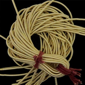 Peut inclure: Un paquet de fil métallique de couleur or, lié ensemble par une ficelle rouge. Le fil est rond et lisse, et il est enroulé en un cercle lâche.