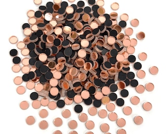 May include: A pile of small, round, mirrored tiles in rose gold and black.
