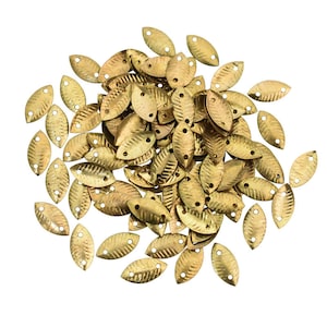 May include: A pile of gold-colored metal leaf-shaped embellishments with two holes in each leaf. The leaves are textured and have a slightly hammered look.