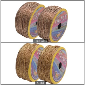 May include: Two spools of gold and rose gold metallic thread. Each spool is labelled "Prince" and "Superfine Quality".