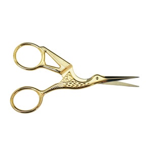 May include: Gold-colored scissors with a bird design. The handles are shaped like a bird's head and the blades are curved.