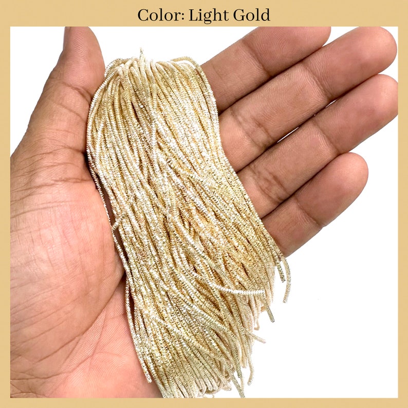 May include: A close-up of a bundle of light gold metallic cord. The cord is thin and has a slightly textured surface.
