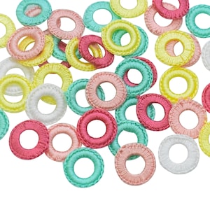 May include: Assortment of colorful crocheted rings in various colors, including pink, yellow, green, and white. The rings are made of soft yarn and have a delicate, handmade look.