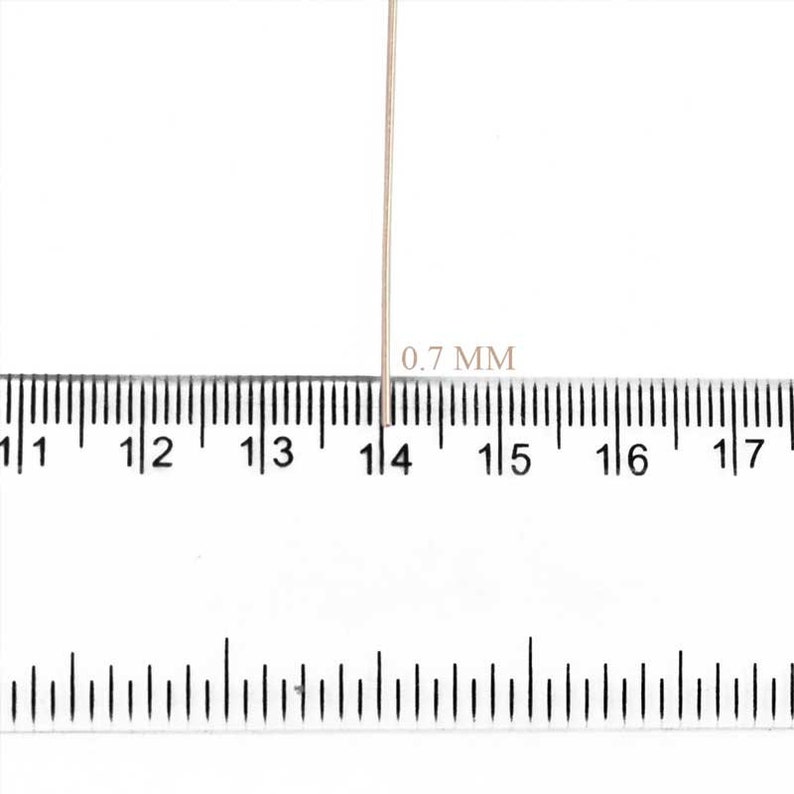 May include: A close-up image shows a thin, light-colored wire next to a ruler. The text "0.7 MM" is printed near the wire, indicating its thickness. The ruler is marked in millimeters, providing a precise measurement reference.