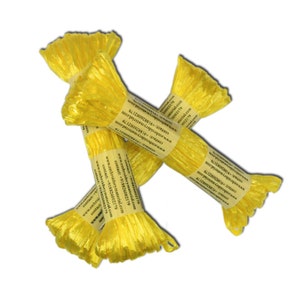 Può includere: Diversi gomitoli di filo da ricamo giallo brillante sono disposti su sfondo bianco. Ogni gomitolo è avvolto con un'etichetta di carta che include informazioni di contatto e un indirizzo web. Il filo ha un aspetto lucido e strutturato.