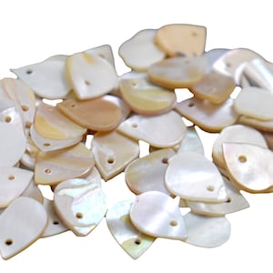 May include: A pile of white and beige iridescent shell teardrop shapes with a hole in the centre. The shells are smooth and have a natural, organic look.
