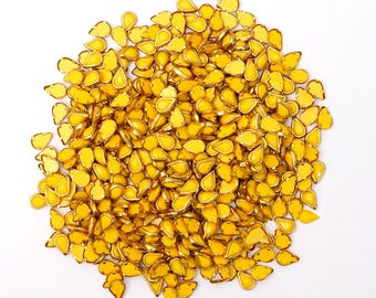 May include: A large pile of yellow teardrop-shaped rhinestones with gold trim.