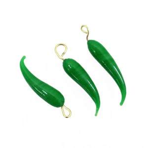 May include: Three green jade chili pepper charms with gold jump rings. The charms are shaped like a chili pepper and have a glossy finish.