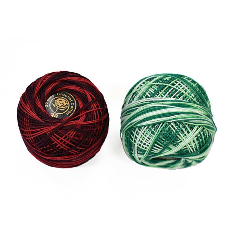 May include: Two balls of crochet cotton yarn. One ball is a deep red and burgundy swirl, with a label that reads "20 gms. Crochet Cotton". The other ball is green and white. Both are on a white background.