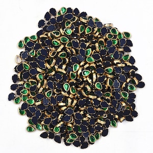 May include: A large pile of green and black teardrop-shaped rhinestones with gold settings. The rhinestones are perfect for adding sparkle to crafts and clothing.
