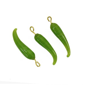 May include: Three green glass chili pepper charms with gold jump rings. The charms are approximately 2 inches long.