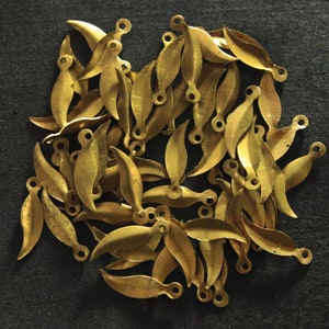 Könnte beinhalten: Ein Haufen goldfarbener, blattförmiger Anhänger aus Metall mit einer kleinen Öse oben.