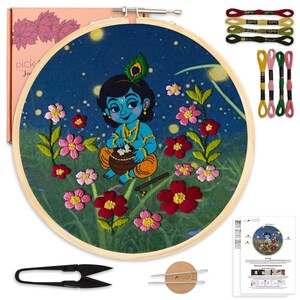 May include: Embroidery kit featuring a cartoon illustration of a blue-skinned deity with a peacock feather, surrounded by flowers. The kit includes embroidery floss, a wooden hoop, scissors, and instructions. The kit comes in a pink box.
