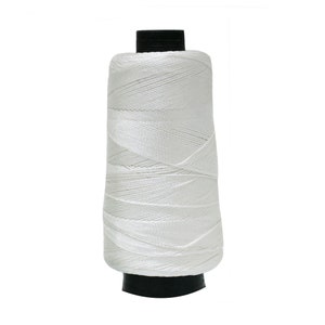 May include: A white spool of thread with a black plastic bobbin.