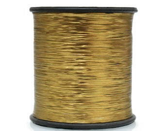 May include: A spool of gold metallic thread. The thread is wound tightly around a black plastic spool.