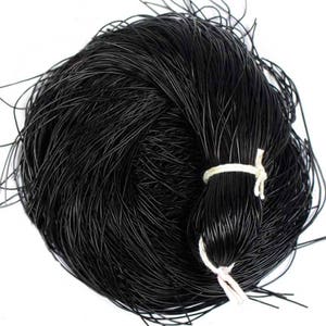 May include: A tightly wound bundle of black cord, secured with a white string tie. The cord appears to be made of a thin, flexible material, and the overall shape is round. The cord is likely used for crafting or other DIY projects.