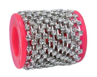 Könnte beinhalten: Eine Rolle silberne Strass-Kettenborte mit klaren Strasssteinen. Die Kette ist um eine rosa Kunststoffspule gewickelt.