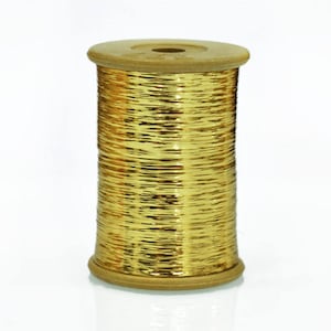 May include: A spool of gold metallic thread wound on a wooden bobbin.