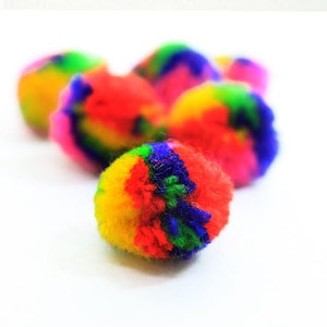 May include: A group of colourful pom-poms in shades of red, yellow, blue, and green. The pom-poms are made of soft, fluffy yarn and are perfect for crafts or decorations.
