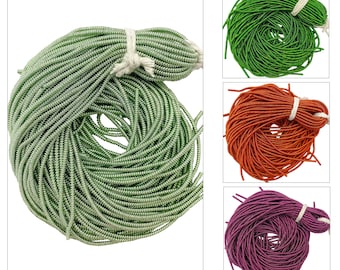 May include: Three spools of metallic cord in green, orange, and purple. The cord is thin and has a slight shimmer.