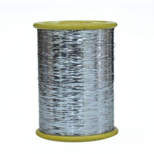 Puede incluir: Una bobina de hilo metálico plateado enrollado en una bobina de plástico amarilla.